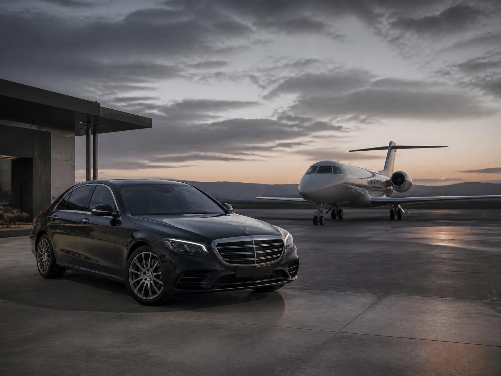 Chauffeured sedan waiting beside a private jet at an FBO terminal