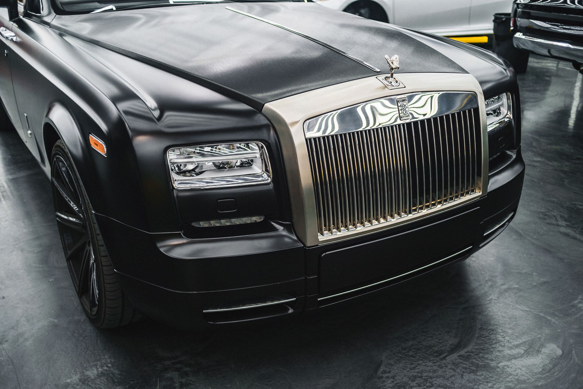 Black Rolls-Royce Phantom with a LEED chauffeur waiting at a Saudi limestone building at dusk